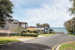A residential street with modern houses, a clear sky, and a view of the sea. - Stillwater House - Poolside Serenity by the Bay (Dunsborough)