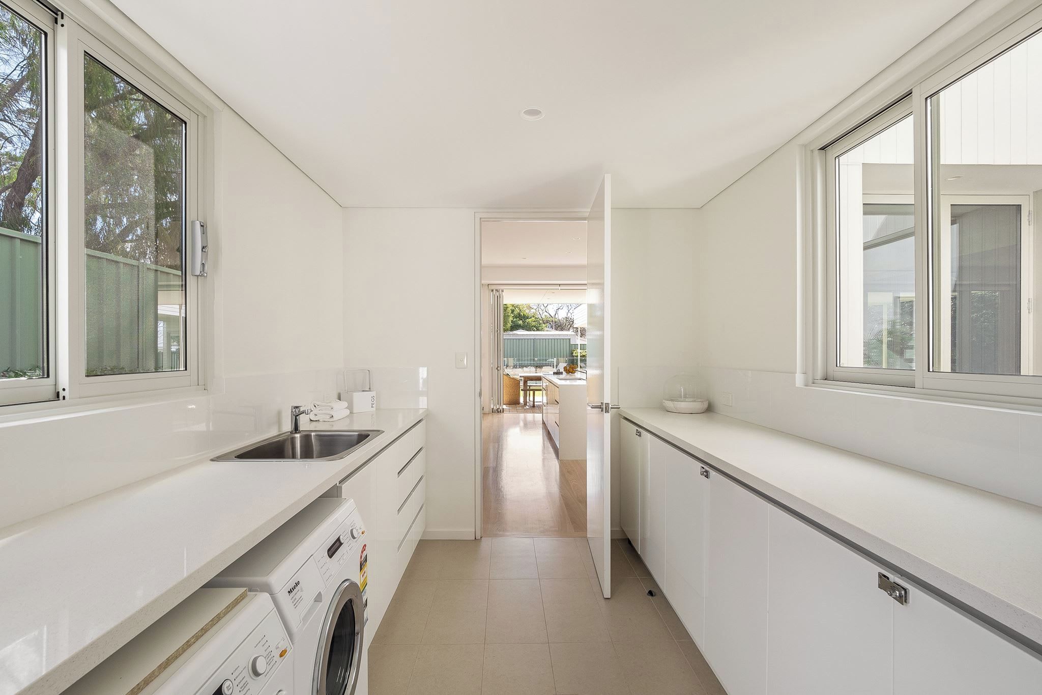 A modern kitchen with a built-in washing machine, a sink, and a view into the dining area.