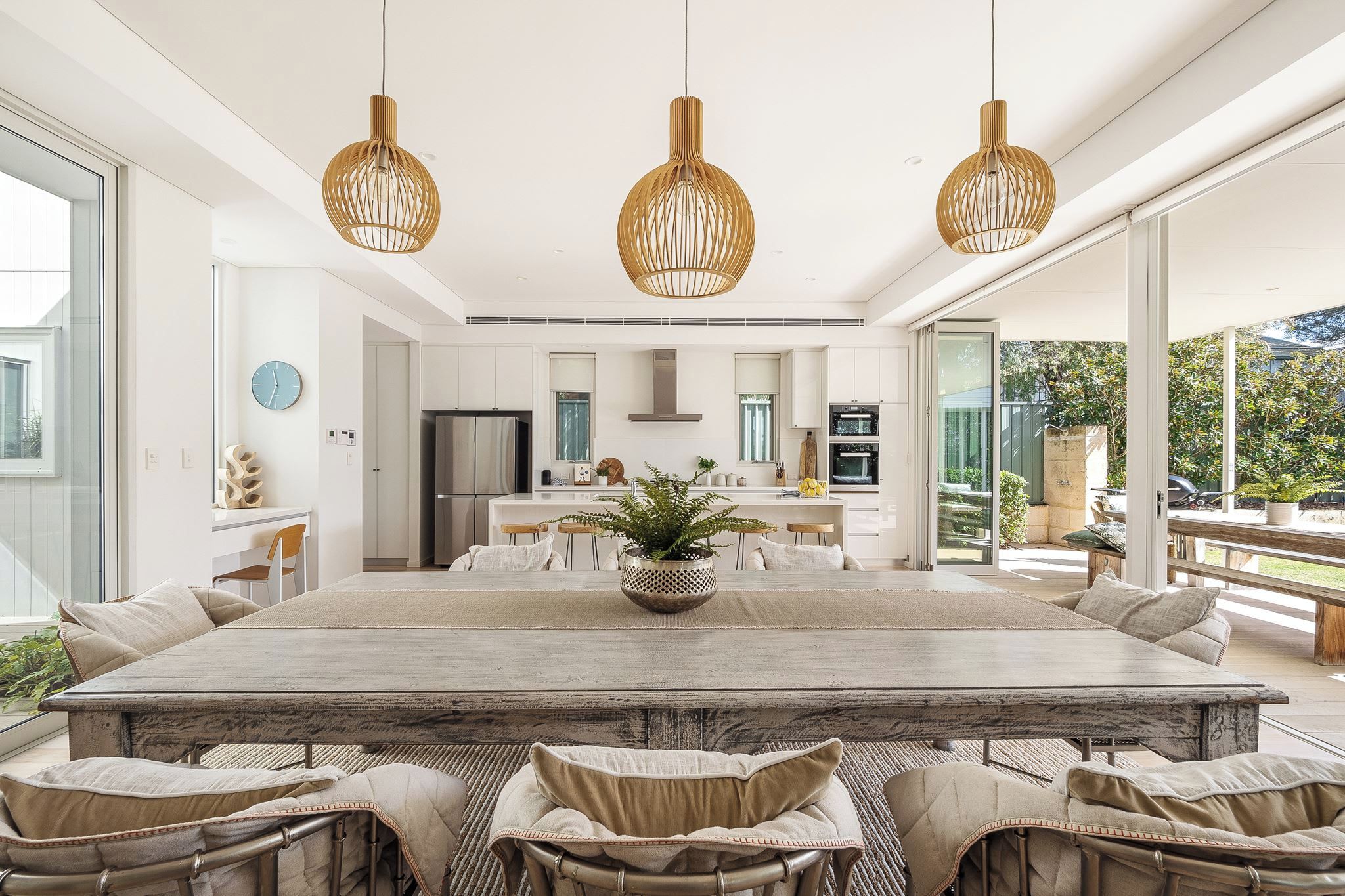 Una cocina moderna con una isla central, electrodomésticos de acero inoxidable y una mesa de comedor grande con sillas.