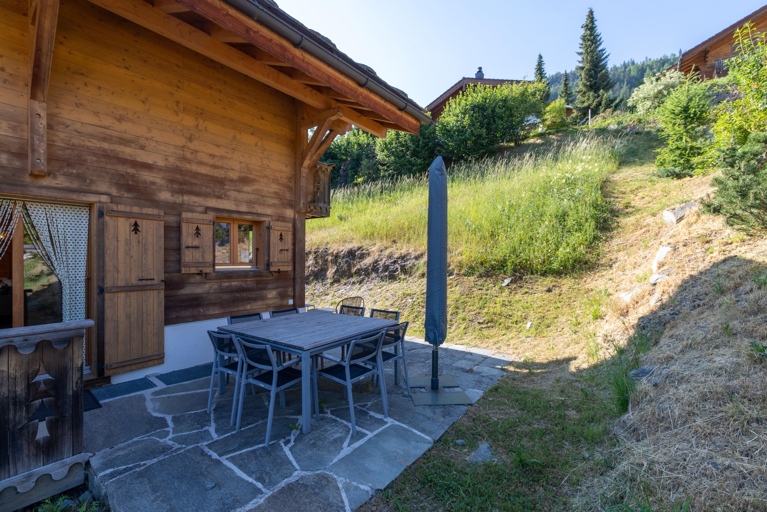 Une cabane en bois avec un patio en pierre, un espace salon extérieur et une vue sur une colline.
