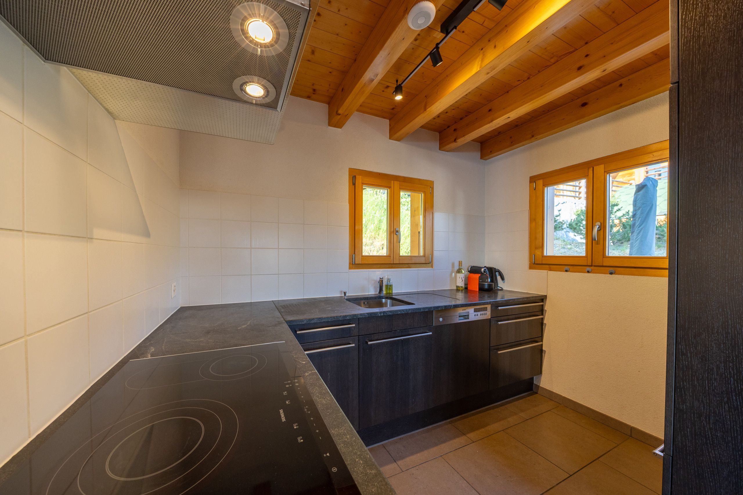 Een moderne keuken met een zwart aanrecht, houten keukenkastjes en een ingebouwde vaatwasser.