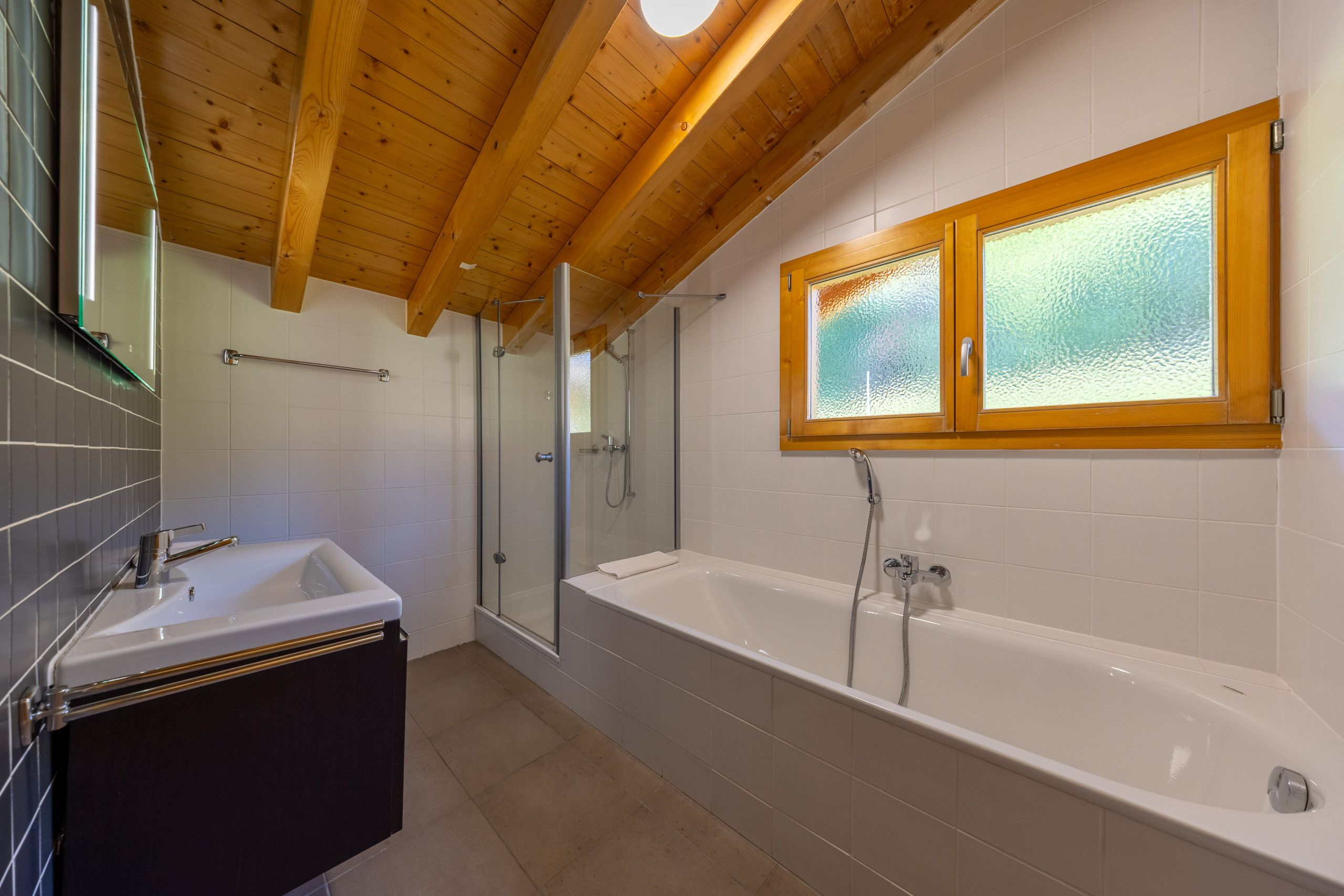Un bagno moderno con vasca, doccia e box doccia in vetro.