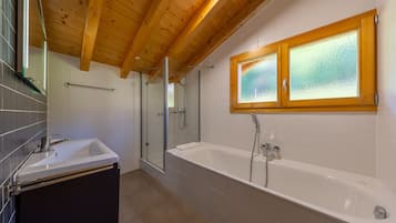 Un bagno moderno con vasca, doccia e box doccia in vetro.