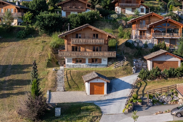 Eine Holzhütte mit Balkon, Garage und Steintreppe.