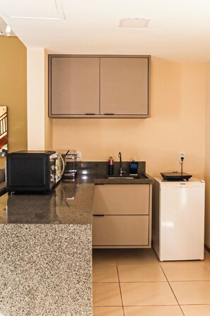 A compact kitchen with a microwave, toaster, sink, and a small refrigerator.
