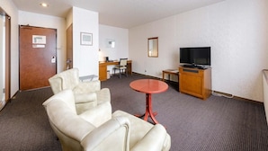 Quarto de hotel com área de estar, televisão e escrivaninha.