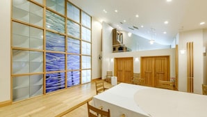 Um quarto amplo com uma grande mesa de jantar, cadeiras de madeira, uma escada e vista através de uma divisória de vidro.