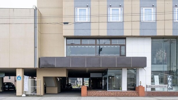 Um edifício moderno com entrada coberta, janelas amplas e uma escadaria visível.