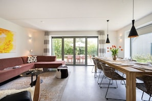 Ein modernes Wohnzimmer mit einer Couch, einem Couchtisch und einem Essbereich mit Stühlen und einem Tisch für zwei Personen.