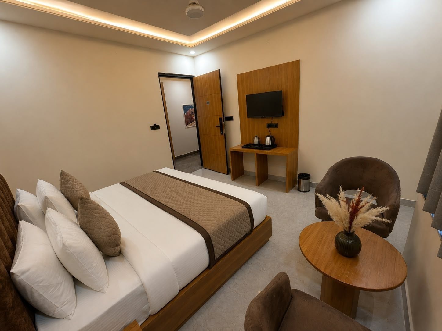 Quarto de hotel moderno com cama, área de estar e televisão.