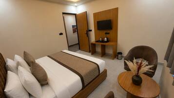 Quarto de hotel moderno com cama, área de estar e televisão.