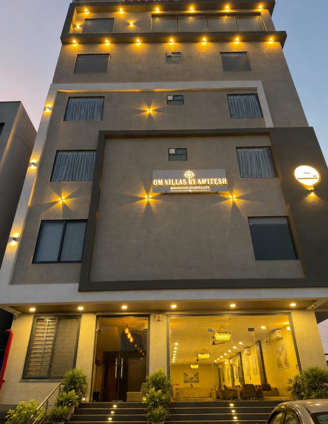 Un hôtel à la façade moderne, doté de nombreuses fenêtres et d’une enseigne indiquant « OM VILLAS BY AMITESH ».