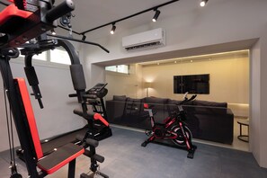 A gym with exercise equipment, a sofa, and a TV in a living area. - Exclusuive offer for you at 88 by spacey (Cairo Governorate)