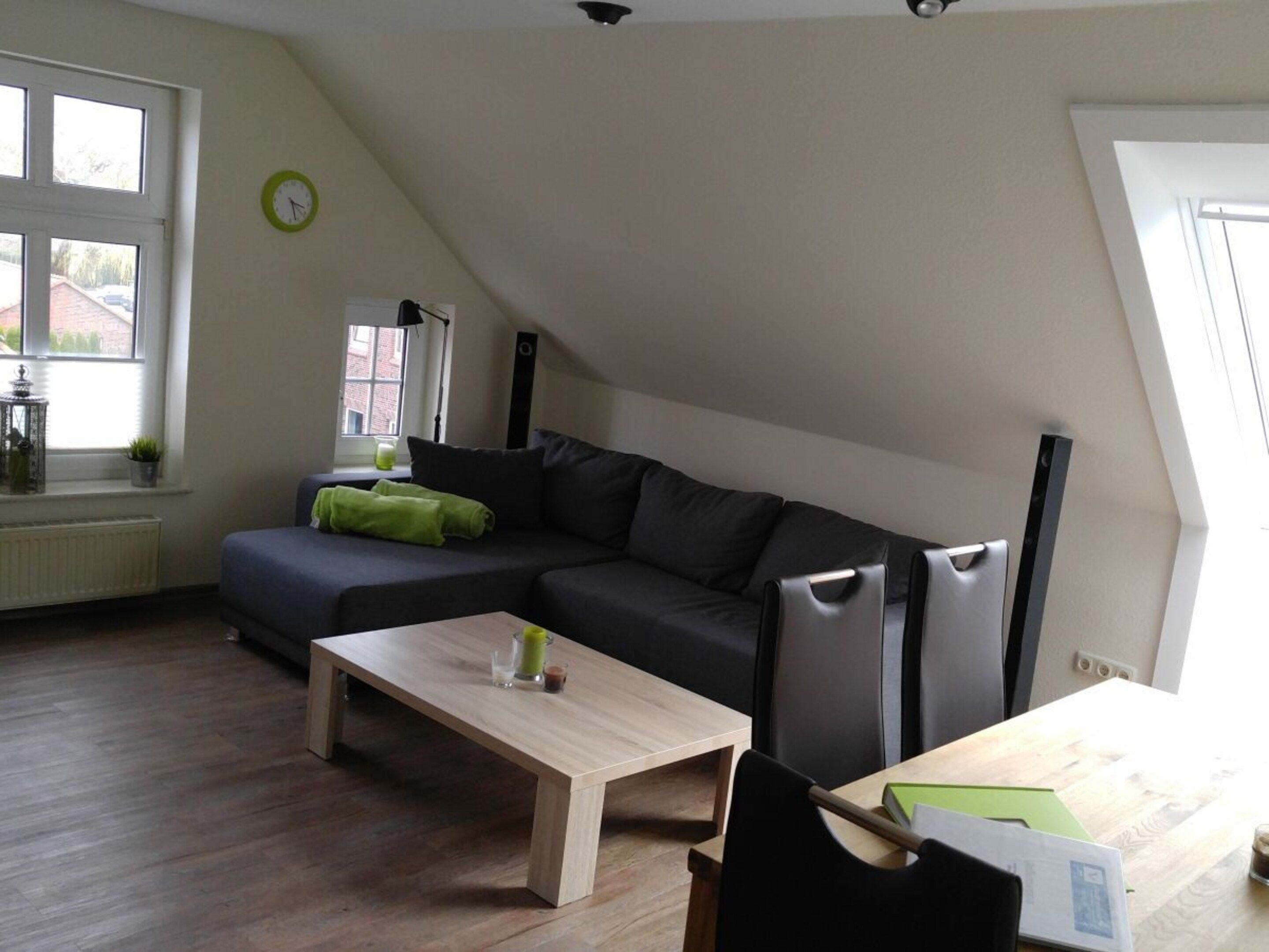 A modern living room with a sectional sofa, a wooden coffee table, and a dining table with chairs.