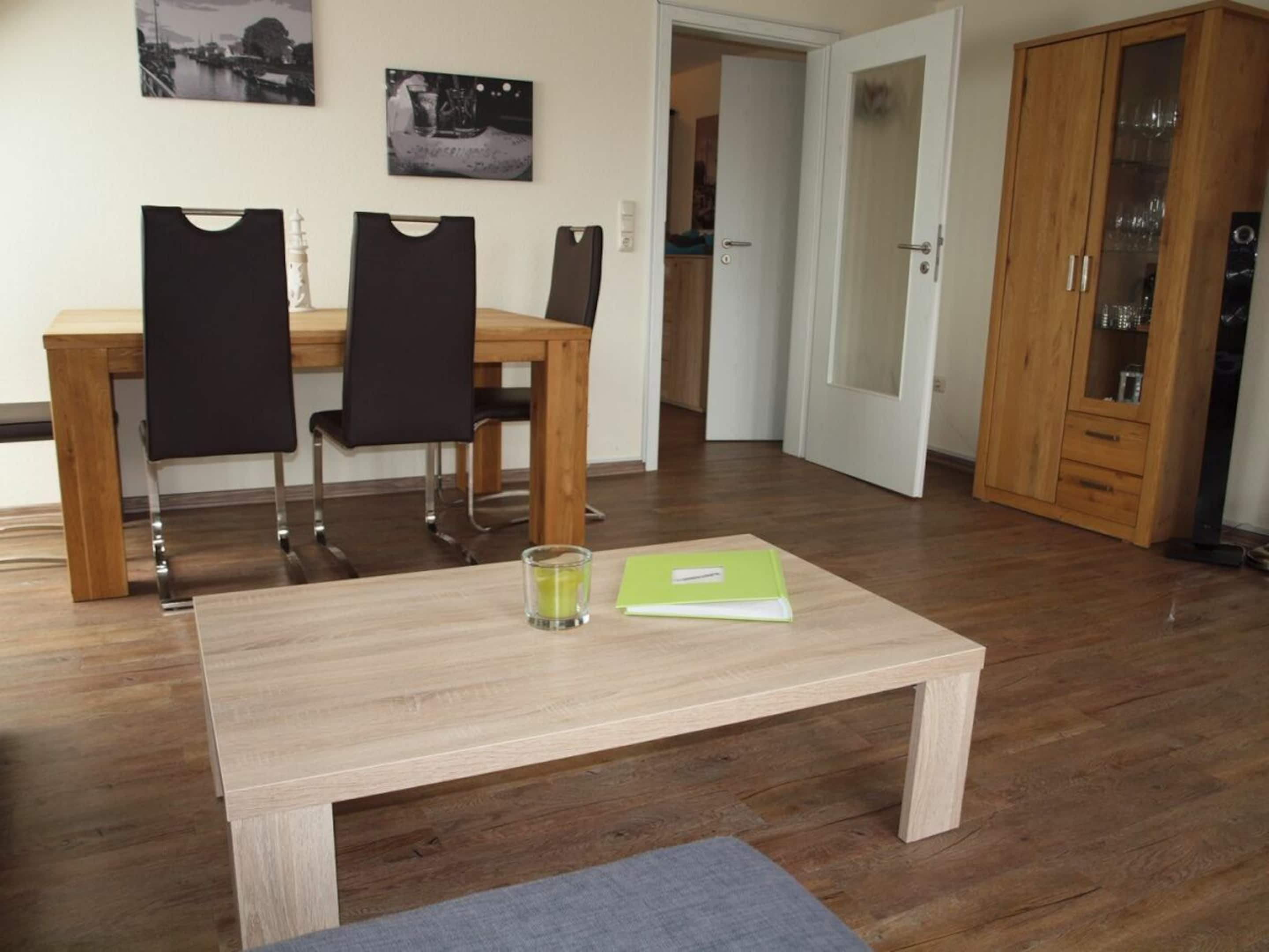 A dining area with a wooden table and chairs, a cabinet with glass doors, and a door leading to another room.