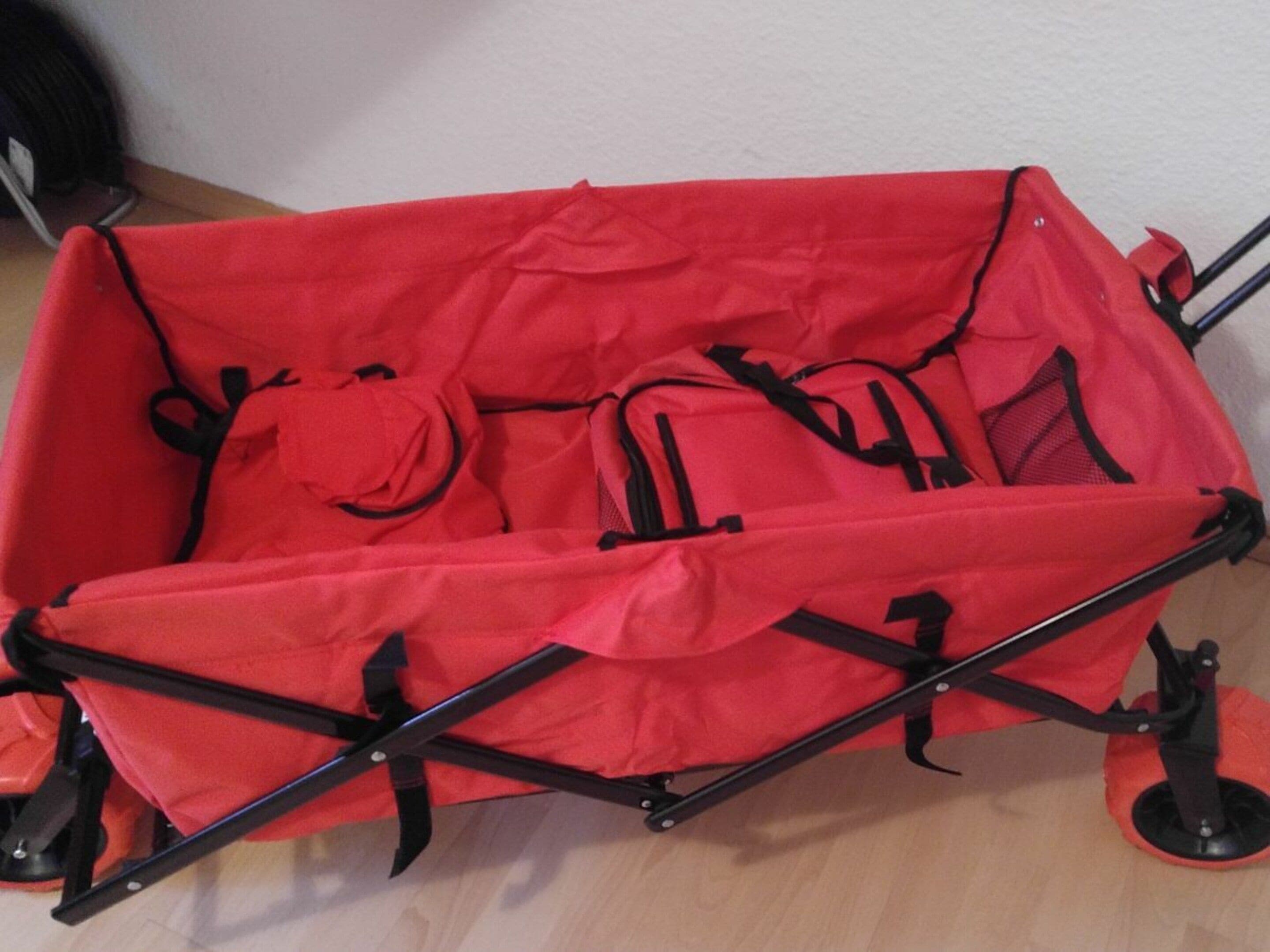 A red stroller with black accents, featuring a foldable design and wheels.