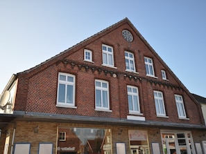 Ein rot genetztes Gebäude mit zahlreichen Fenstern und einer Uhr an der Fassade.