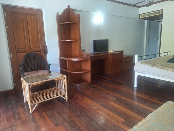 A room with a wooden desk, a television, a bed, a chair, and a wardrobe.