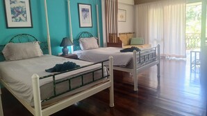 Habitación de hotel con dos camas, una ventana con cortinas y vistas a zonas verdes.