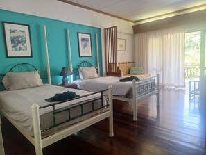 Habitación de hotel con dos camas, una ventana con cortinas y vistas a zonas verdes.