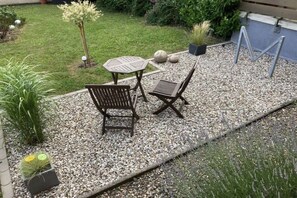 An outdoor seating area with a table and two chairs, surrounded by gravel and plants. - Holiday apartment with 1 bedroom (Goslar)