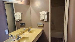 A bathroom with a double sink, a mirror, and a towel rack. - Rodeway Inn (Alamogordo)