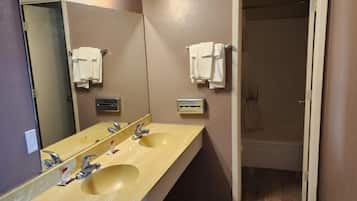 A bathroom with a double sink, a mirror, and a towel rack.
