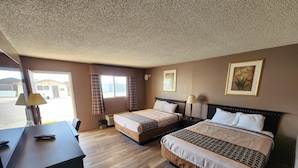 A hotel room with two beds, a desk, and a window with curtains. - Rodeway Inn (Alamogordo)