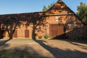 A brick building with a sloped roof, large wooden doors, and potted plants in the foreground. - Holiday home with 2 bedrooms (Frankenfeld)