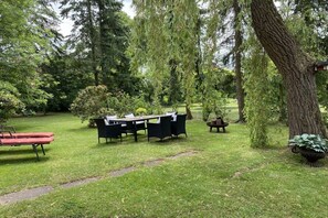 An outdoor seating area with a table and chairs, surrounded by trees and a grassy lawn. - Holiday home with 2 bedrooms (Frankenfeld)