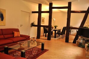 A living room with a red sofa, a glass coffee table, and a dining area with a table and chairs. - Holiday home with 2 bedrooms (Frankenfeld)
