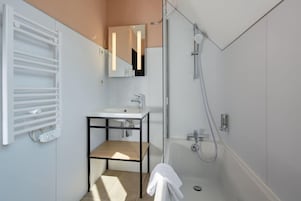 Un baño moderno con calefacción integrada, un lavabo, un espejo y una ducha.