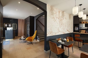 Un moderno vestíbulo de hotel con una recepción, un área de descanso y una escalera.