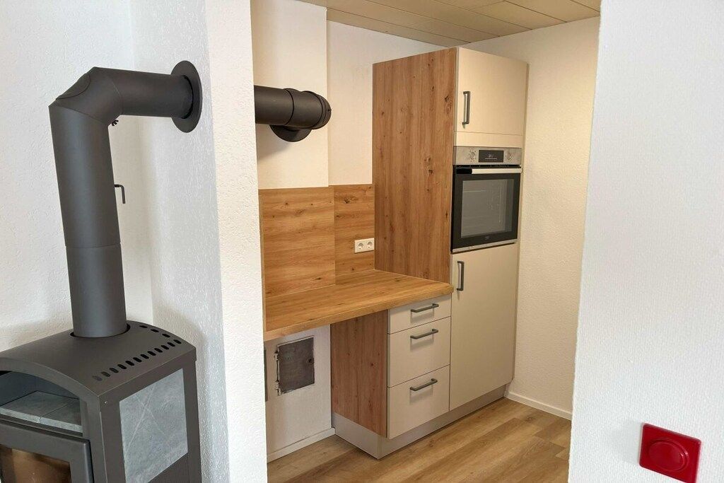 A compact kitchen with a wood-burning stove, a built-in oven, and a wooden countertop.