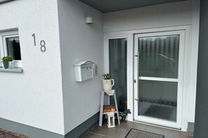 A residential entrance with a white door, a mailbox, a small white lantern, and a potted plant on the wall. - Holiday apartment in Hünstetten with Wi-Fi (Hünstetten)