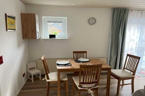 A dining area with a wooden table, four chairs, a clock on the wall, and a window with a view. - Holiday apartment in Hünstetten with Wi-Fi (Hünstetten)