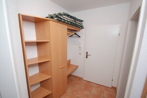 A small, enclosed room with a wooden wardrobe, a door, and a tiled floor. - Schmidt - Mühlenstr. (Prerow)