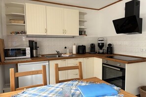 A compact kitchen with white cabinets, a microwave, a coffee maker, and a toaster. - Tom's Stuga Holiday Apartment (Schöneiche)