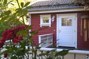 A red building with a white door, a small window, and a white shelf. - Tom's Stuga Holiday Apartment (Schöneiche)