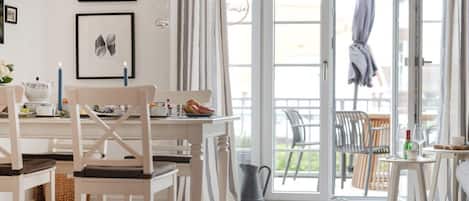 A bright, open-plan living space with a dining area, a large sliding glass door leading to an outdoor area, and a view of the outside.