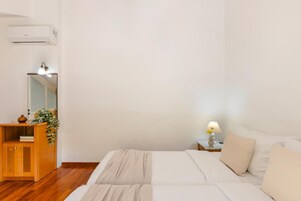 Un dormitorio con una cama, un aparador de madera, un espejo y una lámpara de noche.