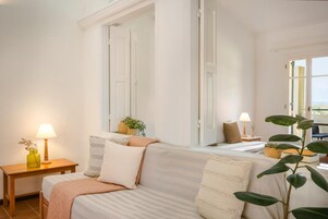 A hotel room with a bed, bedside table, lamp, and a window with a view.