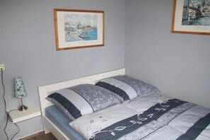 Una camera da letto con un letto, un comodino, una lampada e due quadri appesi al muro.