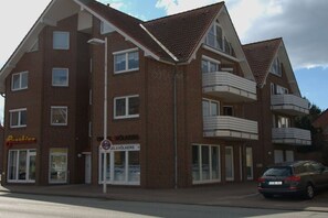 A multi-story building with a brick facade, a shop on the ground floor, and a car parked in front. - Holiday apartment with 2 bedrooms (Stolpe)