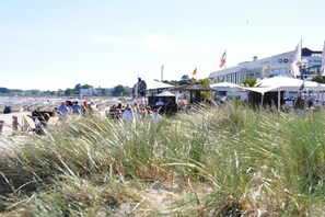 Ett område vid stranden med folk, tält och byggnader.
