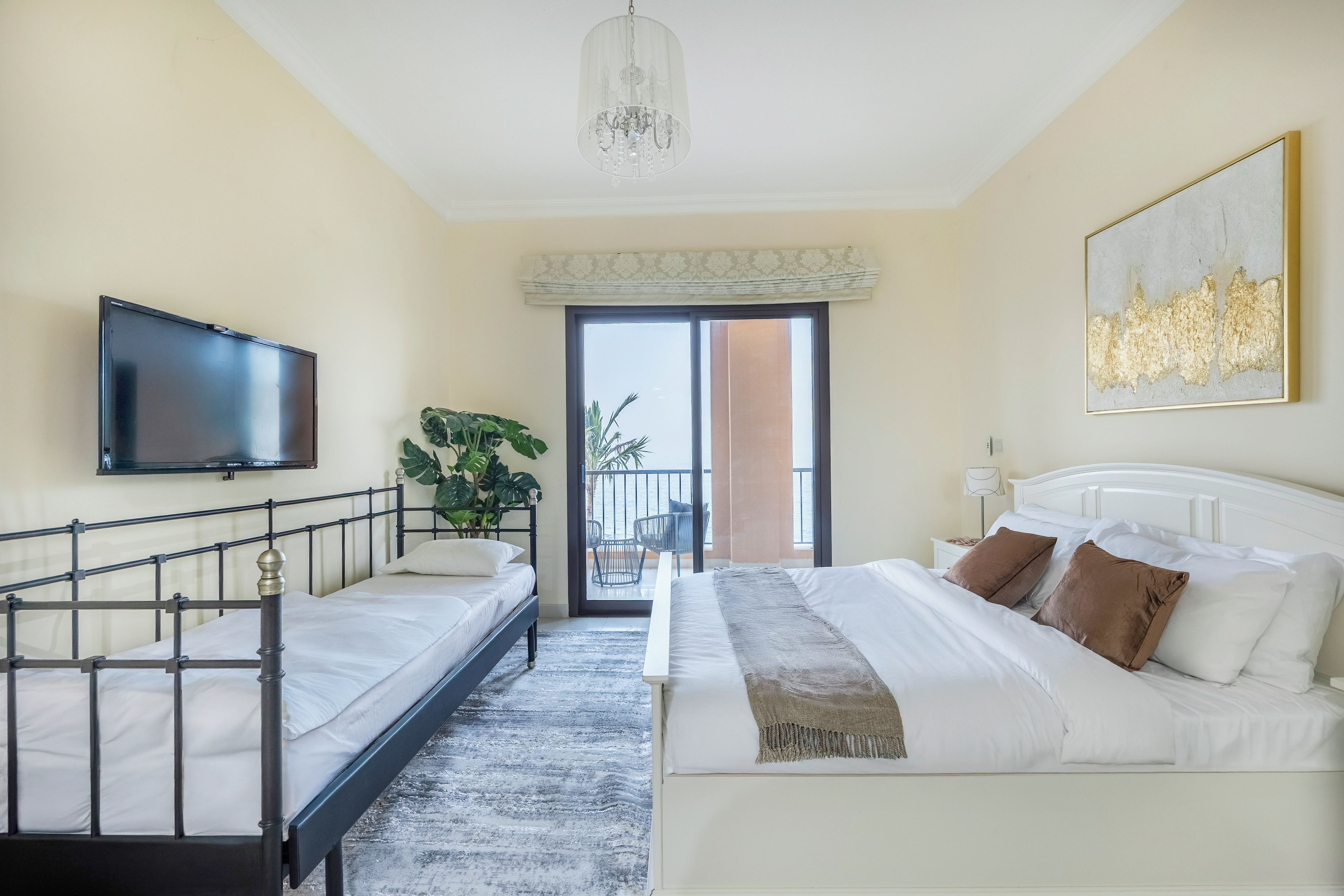 Une chambre d’hôtel avec un lit, une télévision, une plante et un balcon offrant une vue.