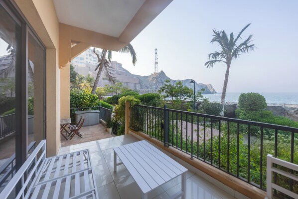 Un balcon avec vue sur la mer, une table, des chaises et une rambarde.