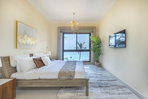 Un dormitorio con una cama grande, una araña de cristal, vistas al mar y una planta en maceta.