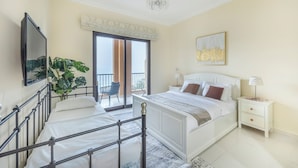 Ein Schlafzimmer mit einem Bett, einem Nachttisch, einem Stuhl, einer Pflanze und Blick ins Freie.