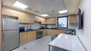 A modern kitchen with stainless steel appliances, wooden cabinets, and a large window.